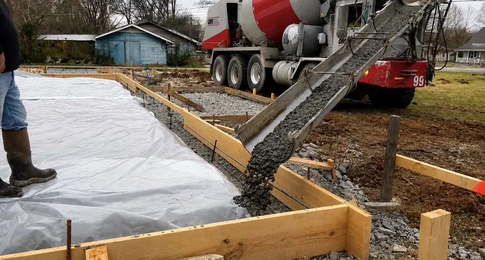 Concrete pouring into formed footings over vapor barrier