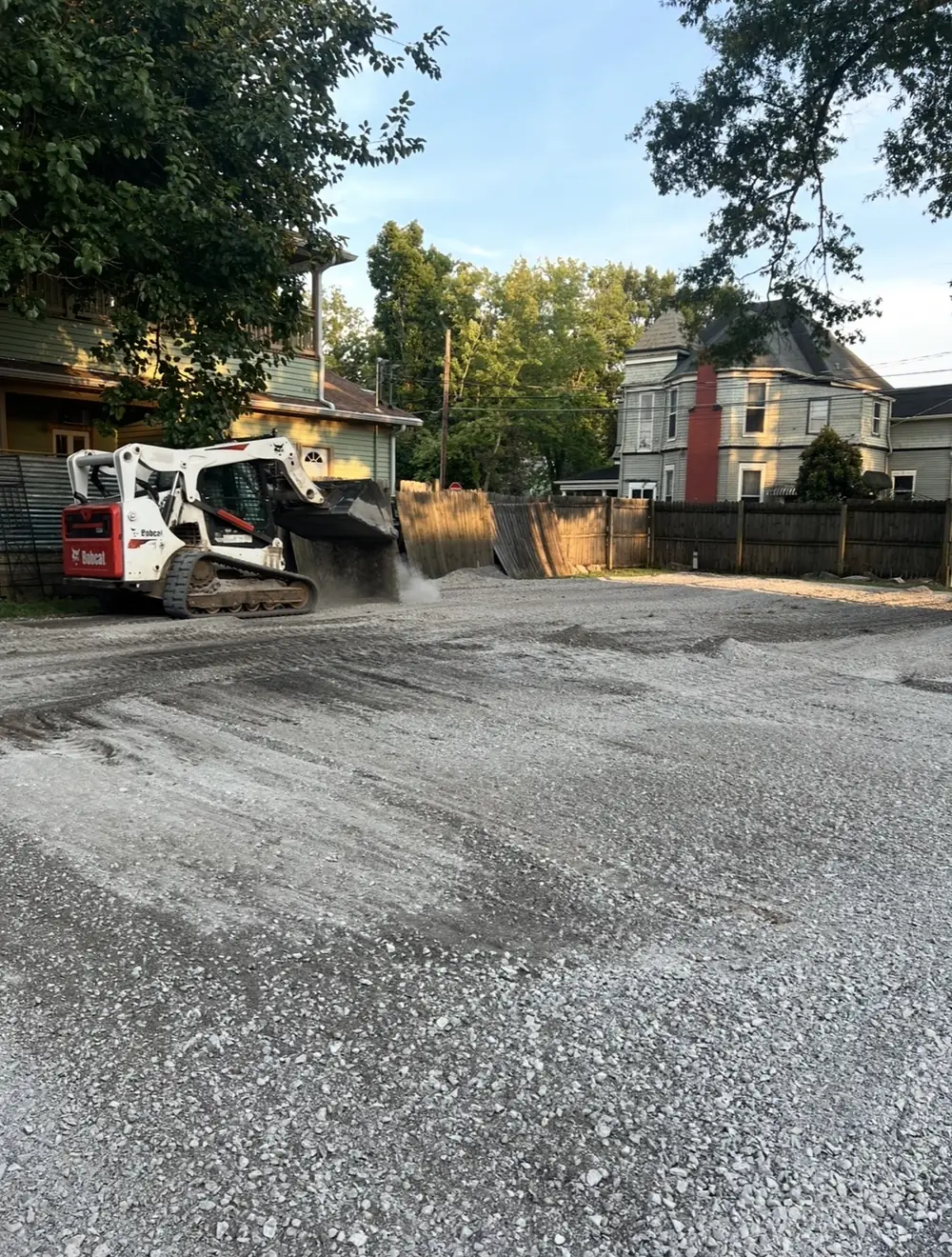 A skid steer spreading gravel on a new pad