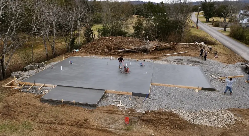 A house slab poured on a cleared red-dirt lot, seen from above